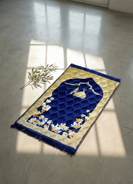 Blue textured jay namaz on a light gray floor with a plant in the corner