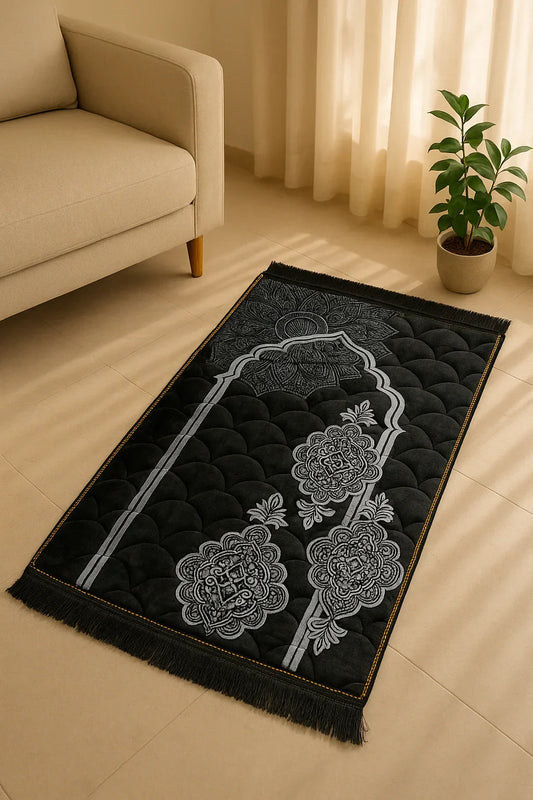 Luxury black velvet Islamic prayer mat with silver floral arch design placed on beige floor near sofa and green plant