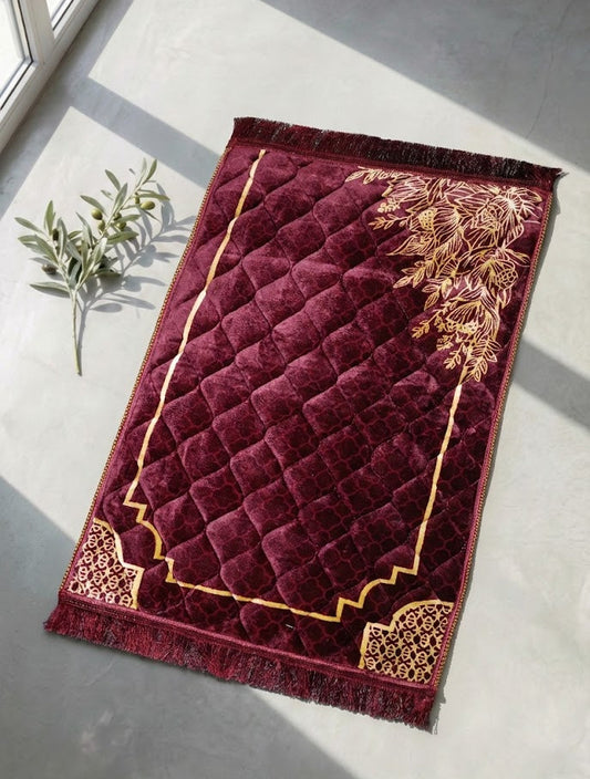 Maroon prayer mat with gold patterns on a light gray floor.