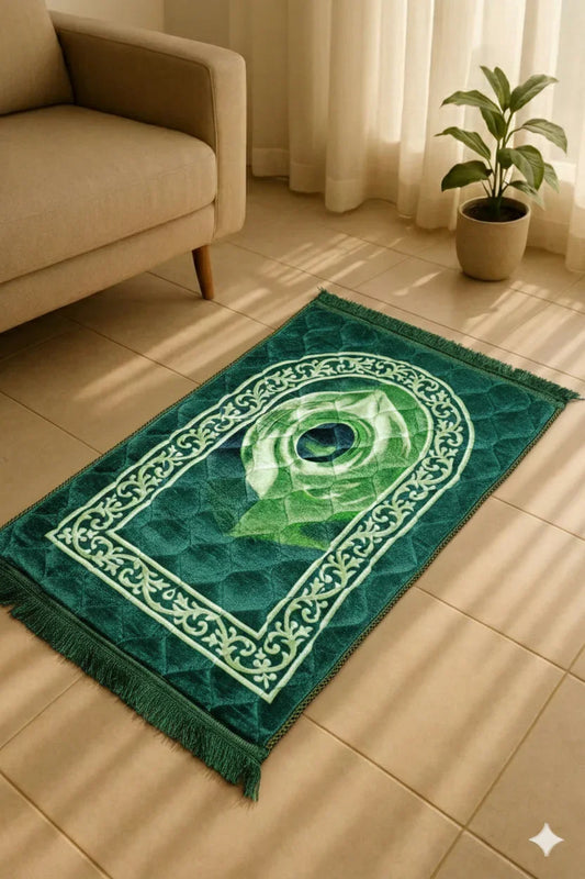 Green Islamic prayer mat with intricate white border patterns on beige tile floor next to sofa and plant