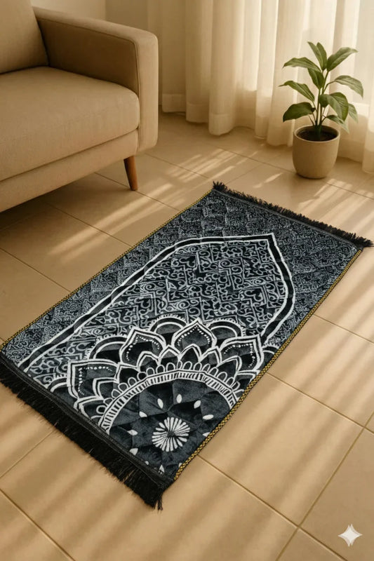 Black and white Islamic prayer mat with intricate geometric and floral designs placed on floor near beige sofa and potted plant