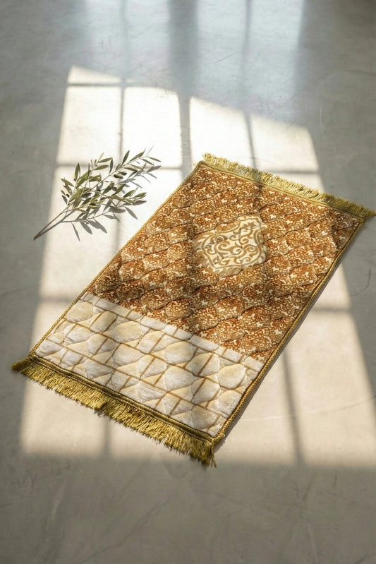 Soft velvet gold Jay namaz or prayer mat and white rug with intricate patterns on a light gray floor.